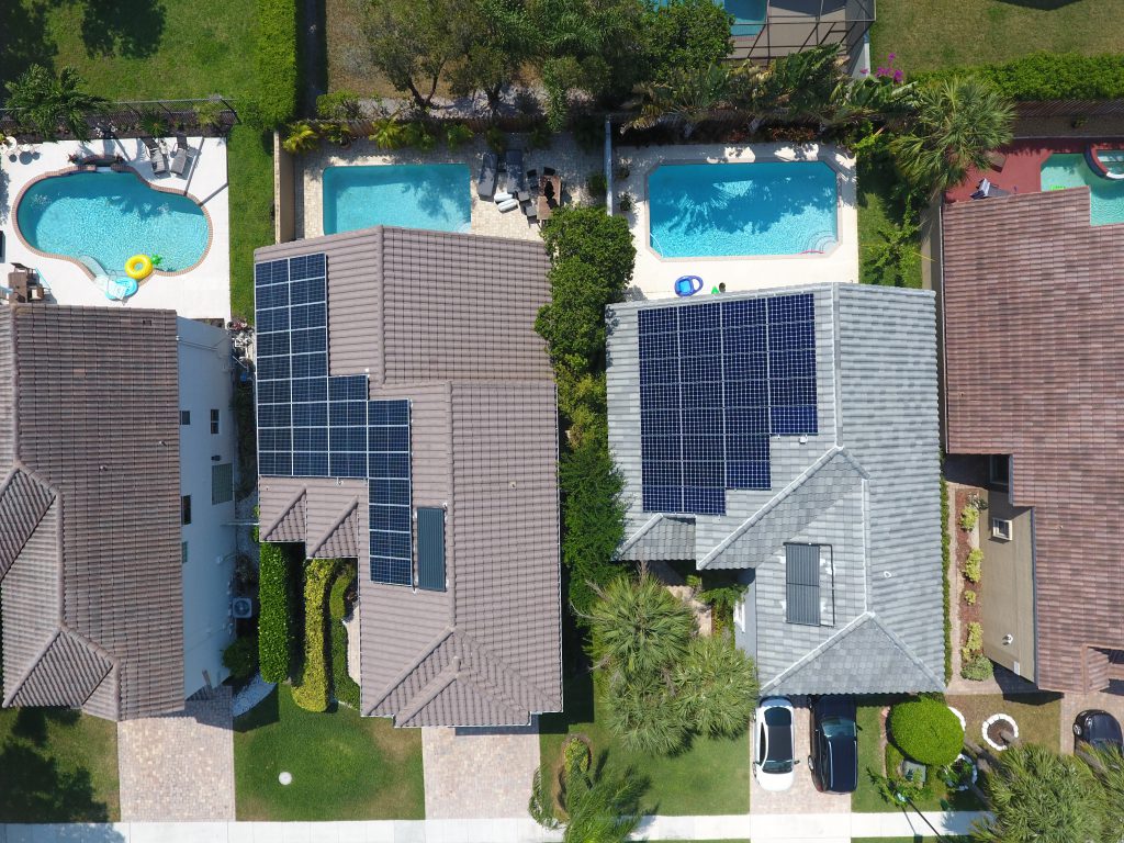 Toma aérea de tres viviendas equipadas con sistemas de calefacción solar para piscinas